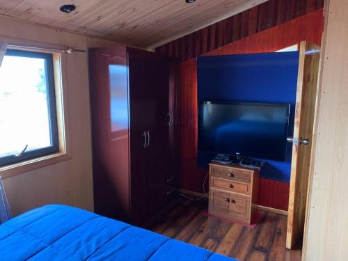 达卡卫Casa Centro Dalcahue的一间卧室配有一张床和一台平面电视