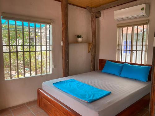 宁平LITTLE TRANG AN HOMESTAY的一间卧室配有一张带蓝色枕头的床和窗户。