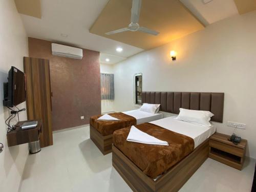 孟买HOTEL DIVINE的一间卧室配有两张床和一台平面电视