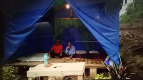 TukumGlamping Kalimarno Wonosalam的两个男人坐在一个蓝色的帐篷里