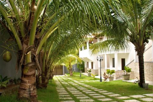 马塔迪圣若昂Residencial Jardim Imbassai 4 apt mobiliado com piscina的房子的院子中的棕榈树