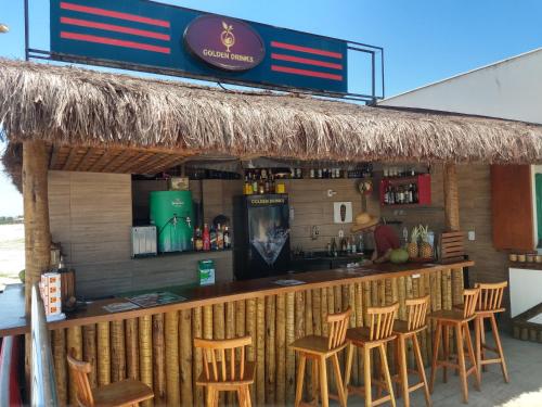 阿拉亚尔-杜卡布Apartamento no Golden Lake - pé na areia, agua de côco e cervejinha的酒吧设有木凳和吧台