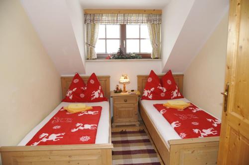 毛特恩多夫Landhaus Gartler的阁楼间内的两张床,配有红色枕头