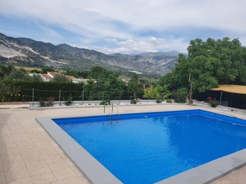 格拉纳达Casa rural en Padul entre Sierra Nevada y la Costa的一个大型蓝色游泳池,后面是群山