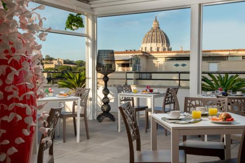 罗马Fragrance Hotel St. Peter的餐厅设有桌椅,享有圆顶的景致。