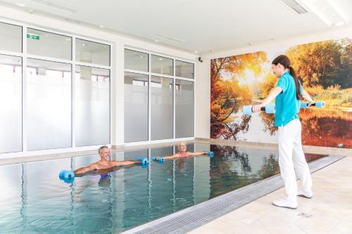 OberzeiringGesundheits- & Wellness Resort Oberzeiring的女人在带有壁画的游泳池里锻炼