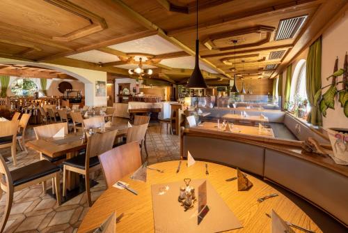 坦海姆Gasthof Enzian的一间带木桌椅的餐厅和一间酒吧