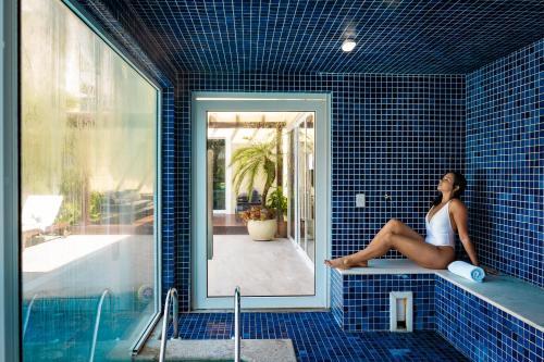 帕拉蒂Pousada Apple House Paraty的坐在蓝色瓷砖浴室的浴缸里的女人