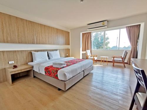 梭桃邑Sea Paradise Hotel Sattahip的酒店客房带一张床、一张桌子和椅子