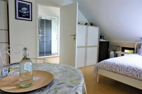 EsneuxLe Jardin des Miroirs的一间卧室配有一张床和一张桌子上的一瓶