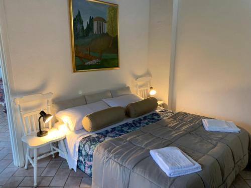 Le CerqueteCasetta degli Ulivi Maccarese的一间卧室配有一张床和一张带台灯的桌子