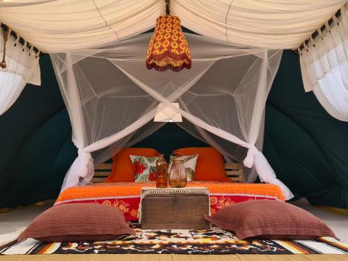 Ban Nong TakhainVilla Noina Glamping的帐篷内的一张床位,配有枕头和桌子