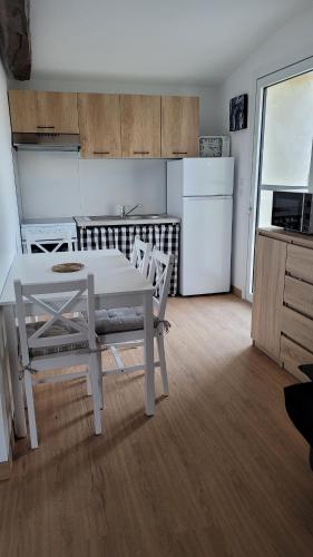 NoirlieuGite le Petit Doué的厨房配有白色的桌椅和冰箱。