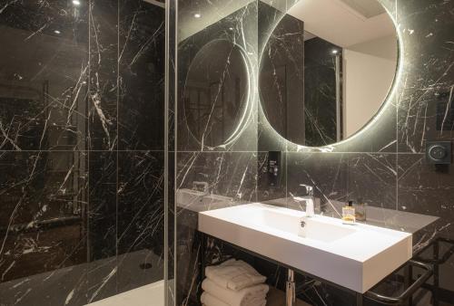 Ballan-MiréKYRIAD Tours Sud - Ballan Mire的浴室配有盥洗盆和带镜子的淋浴