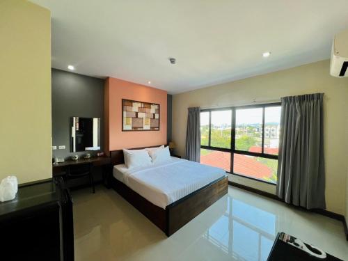 南邦马别致及舒适公寓式酒店的一间卧室配有一张床、一台电视和一个窗口