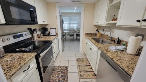 希尔顿黑德岛HHI Homes LLC的厨房配有白色橱柜、水槽和微波炉