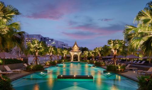 曼谷察殿曼谷大酒店的度假村的游泳池,种植了棕榈树,设有宝塔