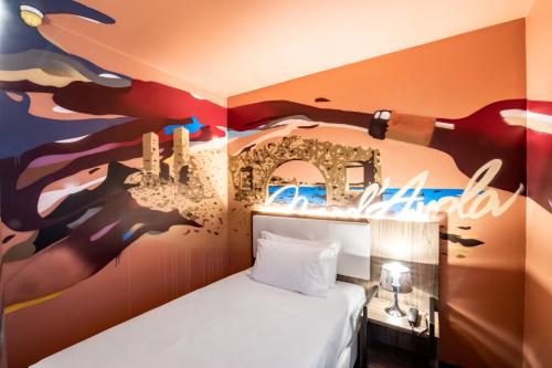 卡斯泰尔达扎诺Muraless Art Hotel的一间设有一张床的客房,墙上挂着一幅画