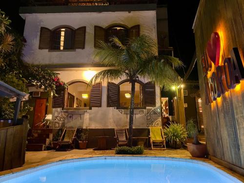 阿拉亚尔-杜卡布A Coroa Hostel & Suites的夜间在房子前面的游泳池