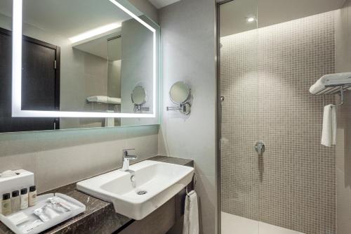 阿可贺巴Somerset Downtown Al Khobar的浴室配有盥洗盆和带镜子的淋浴