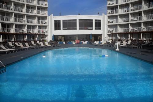 弗吉尼亚海滩海滨套房品质酒店的一座带椅子的大型游泳池和一座建筑
