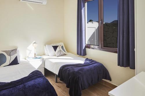 普拉亚布兰卡Villa Cantium - LH101 By Villas Now Ltd的带窗户的客房内的两张床