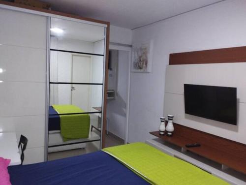 维多利亚Apartamento bairro Praia do Canto na Reta da Penha的一间卧室配有一张床,墙上配有电视
