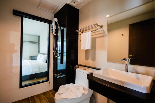 合艾JS HOTEL的一间带水槽、卫生间和镜子的浴室