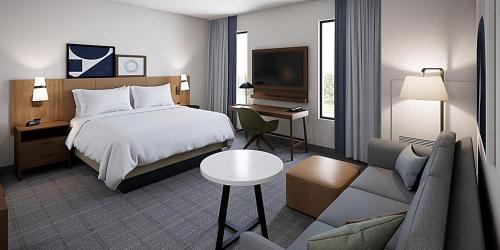 辛辛那提Staybridge Suites - Cincinnati East - Milford, an IHG Hotel的一间卧室配有一张床、一张桌子和一张沙发