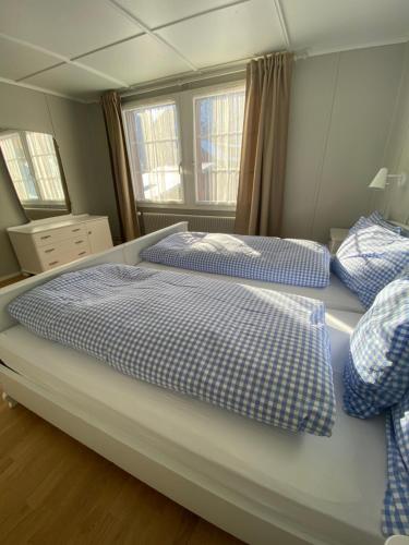 坎德施泰格Familienferien im Chalet Bärgli Kandersteg的一间卧室配有两张带蓝白色床单的床