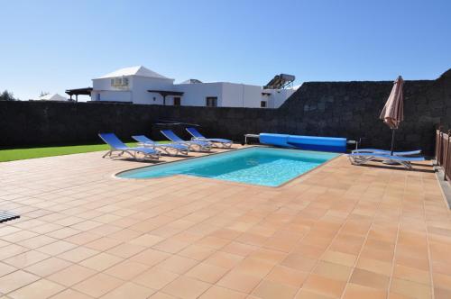 普拉亚布兰卡Villa Esmeralda的一个带躺椅和遮阳伞的游泳池