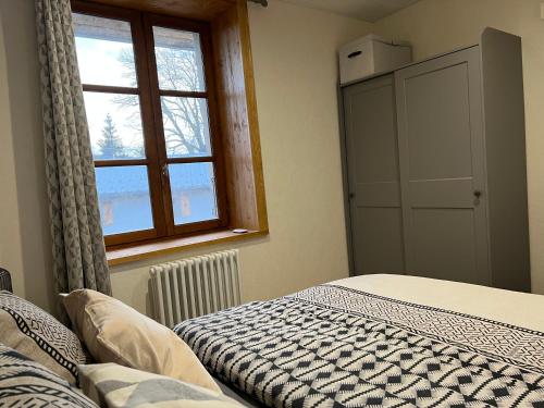 Entre-Deux-MontsMaison rénovée au cœur du Haut-Jura的一间卧室设有一张床和一个窗口