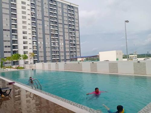 甘榜龙溪KAMI HOLIDAY HOME with SWIMMING POOL的两人在一座大建筑内的游泳池里
