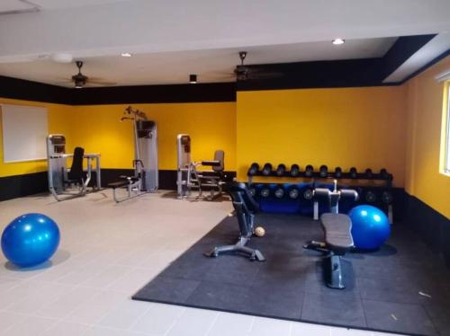 甘榜龙溪KAMI HOLIDAY HOME with SWIMMING POOL的一间健身房,里面设有运动器材,房间拥有黄色的墙壁
