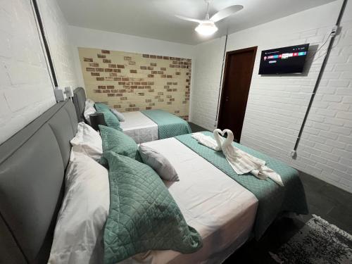 莫雷蒂斯Pousada Trilha da Serra的两张床铺,房间墙上配有电视