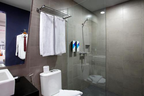 塞米亚克Berry Biz Hotel Sunset Road的一间带卫生间和玻璃淋浴间的浴室