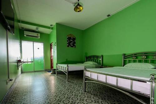 合艾2U Hotel Hatyai的绿色的客房设有两张床和窗户。