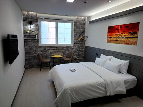平泽市Hi& Hotel的一间卧室配有一张床、一张桌子和一个窗户。