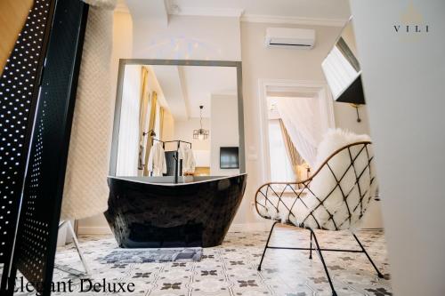 奥拉迪亚Vili Apartments的带浴缸、椅子和镜子的浴室
