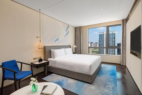 上海上海大华长风华邑酒店的一间卧室配有一张床、一把蓝椅和一个窗户。