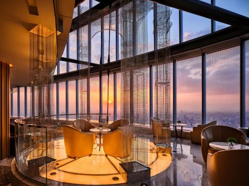 上海J酒店上海中心（申城之巅 俯瞰外滩）的餐厅在大窗户前设有玻璃桌和椅子