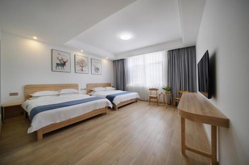 武夷山千浔茶舍的酒店客房设有两张床和一张桌子。