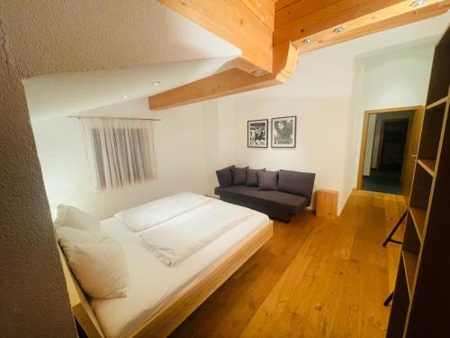 翁肯Natursport Heutal Appartements的一间带床和沙发的小卧室
