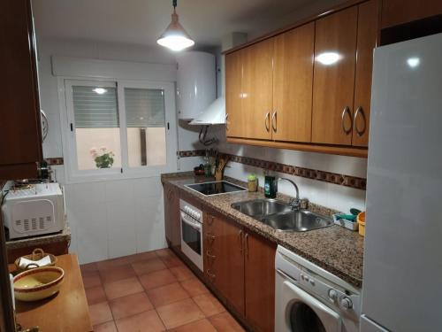 圭哈尔谢拉Apartamento Guejar Sierra的厨房配有木制橱柜、水槽和洗碗机。