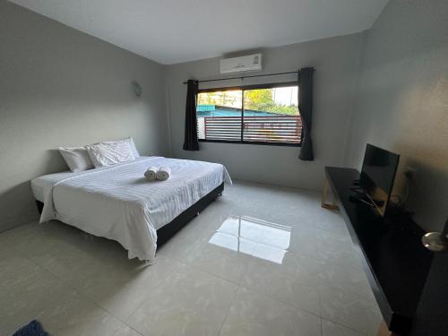 甲米镇红松之家酒店的一间卧室配有一张床、一台电视和一个窗口
