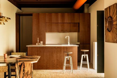 塞维利亚BOSCOS APARTMENTs的厨房配有木制橱柜和带凳子的台面