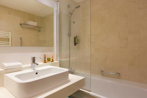 巴黎馨乐庭巴黎歌剧院旅馆的白色的浴室设有水槽和淋浴。