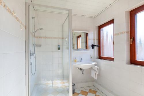 Wächtersbach祖尔奎勒兰德酒店的带淋浴和盥洗盆的白色浴室