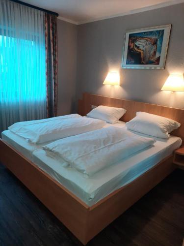 Esselbach塔布里克酒店的卧室配有一张带白色床单和枕头的大床。