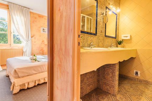 莱塞齐耶德泰阿克Hostellerie du Passeur - Hôtel & Restaurant - Climatisation et Piscine chauffée的一间带水槽的浴室和一张位于客房内的床